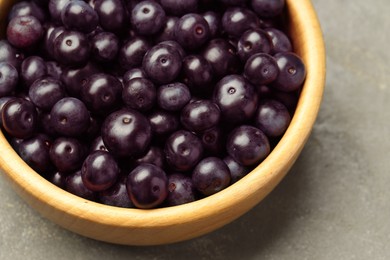 Photo of Ripe acai berries in bowl on grey textured table, above view