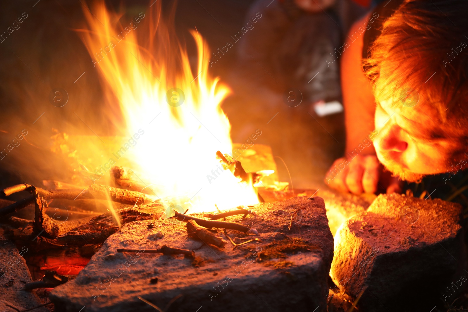 Photo of Man making bonfire in forest at night, closeup