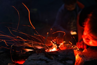 Photo of Man making bonfire in forest at night, closeup