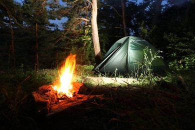 Photo of Bonfire and camping tent in forest at night