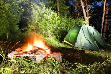 Photo of Bonfire and camping tent in forest at night