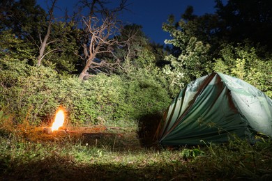 Photo of Bonfire and camping tent in forest at night