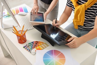 Photo of Designers working together with tablets at table in office, closeup