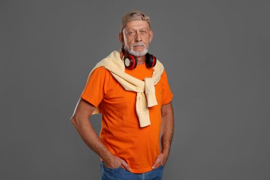 Portrait of handsome senior man with headphones on grey background