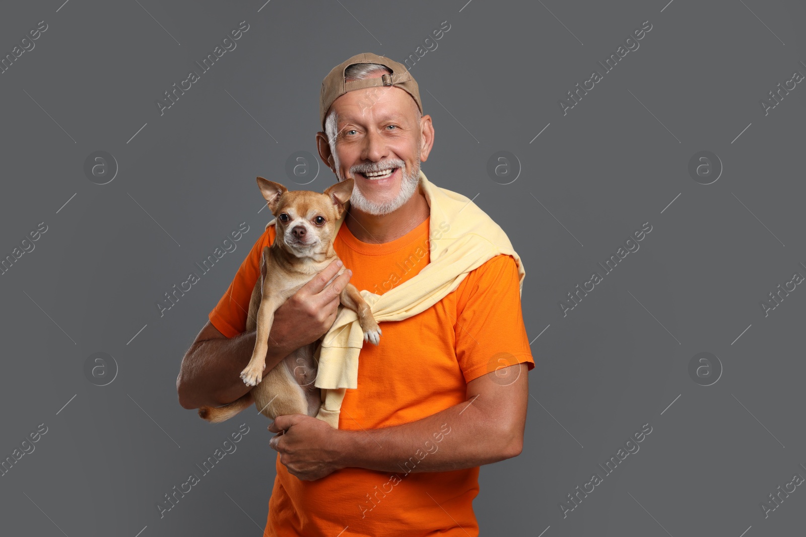 Photo of Portrait of happy senior man with cute Chihuahua dog on grey background