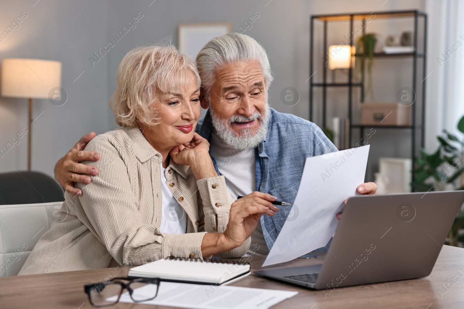 Photo of Pension savings. Senior couple planning budget at wooden table indoors