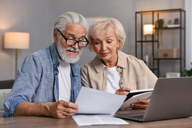 Pension savings. Senior couple planning budget at wooden table indoors