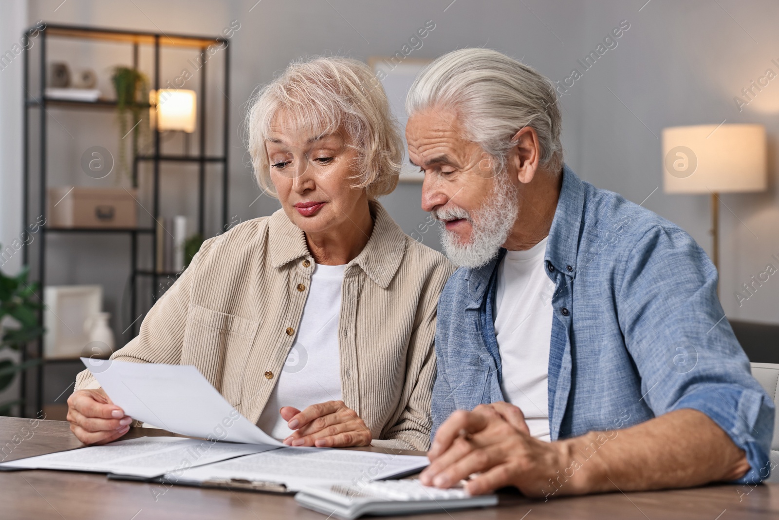 Photo of Pension savings. Senior couple planning budget at wooden table indoors