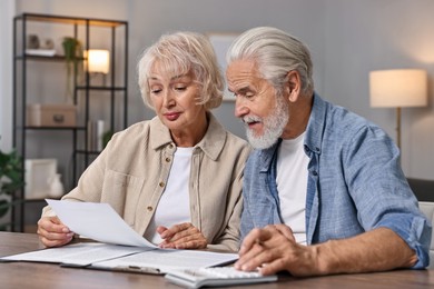 Pension savings. Senior couple planning budget at wooden table indoors