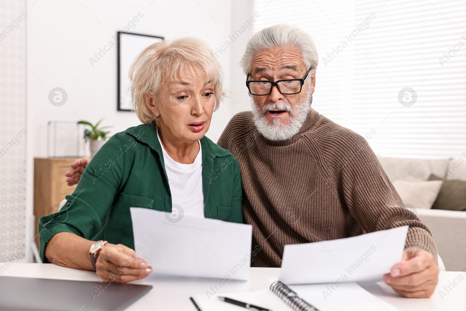 Photo of Pension savings. Senior couple planning budget at white table indoors