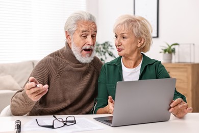 Photo of Pension savings. Senior couple planning budget at white table indoors