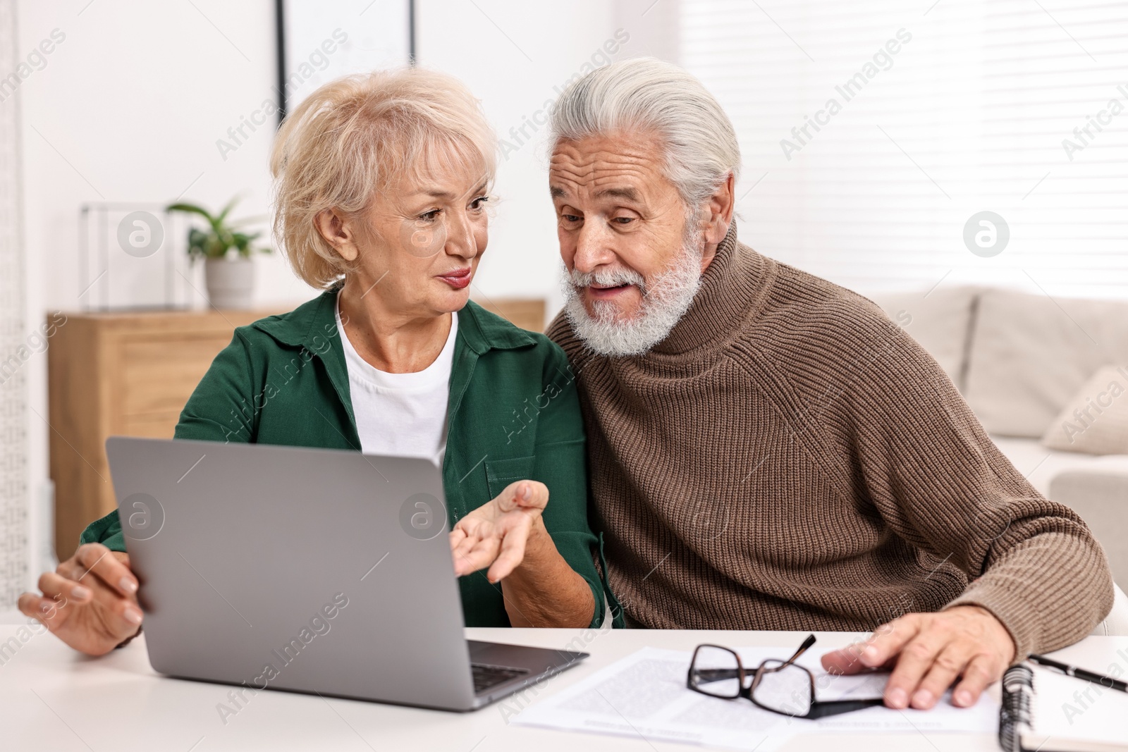 Photo of Pension savings. Senior couple planning budget at white table indoors