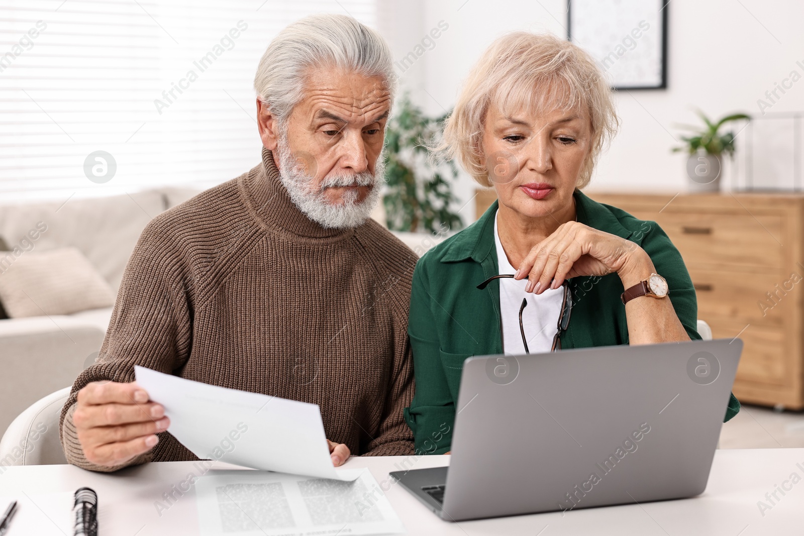 Photo of Pension savings. Senior couple planning budget at white table indoors