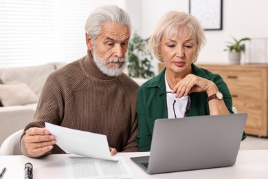 Pension savings. Senior couple planning budget at white table indoors