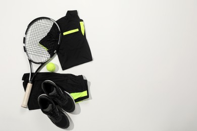 Photo of Tennis racket, ball and sportswear on white background, flat lay. Space for text