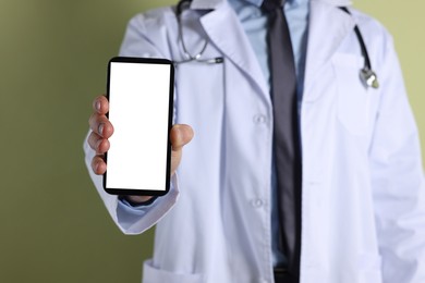 Doctor showing smartphone with blank screen on olive background, closeup. Mockup for design