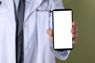 Doctor showing smartphone with blank screen on olive background, closeup. Mockup for design