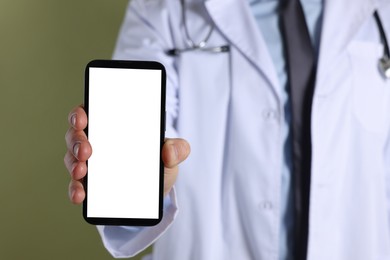 Doctor showing smartphone with blank screen on olive background, closeup. Mockup for design