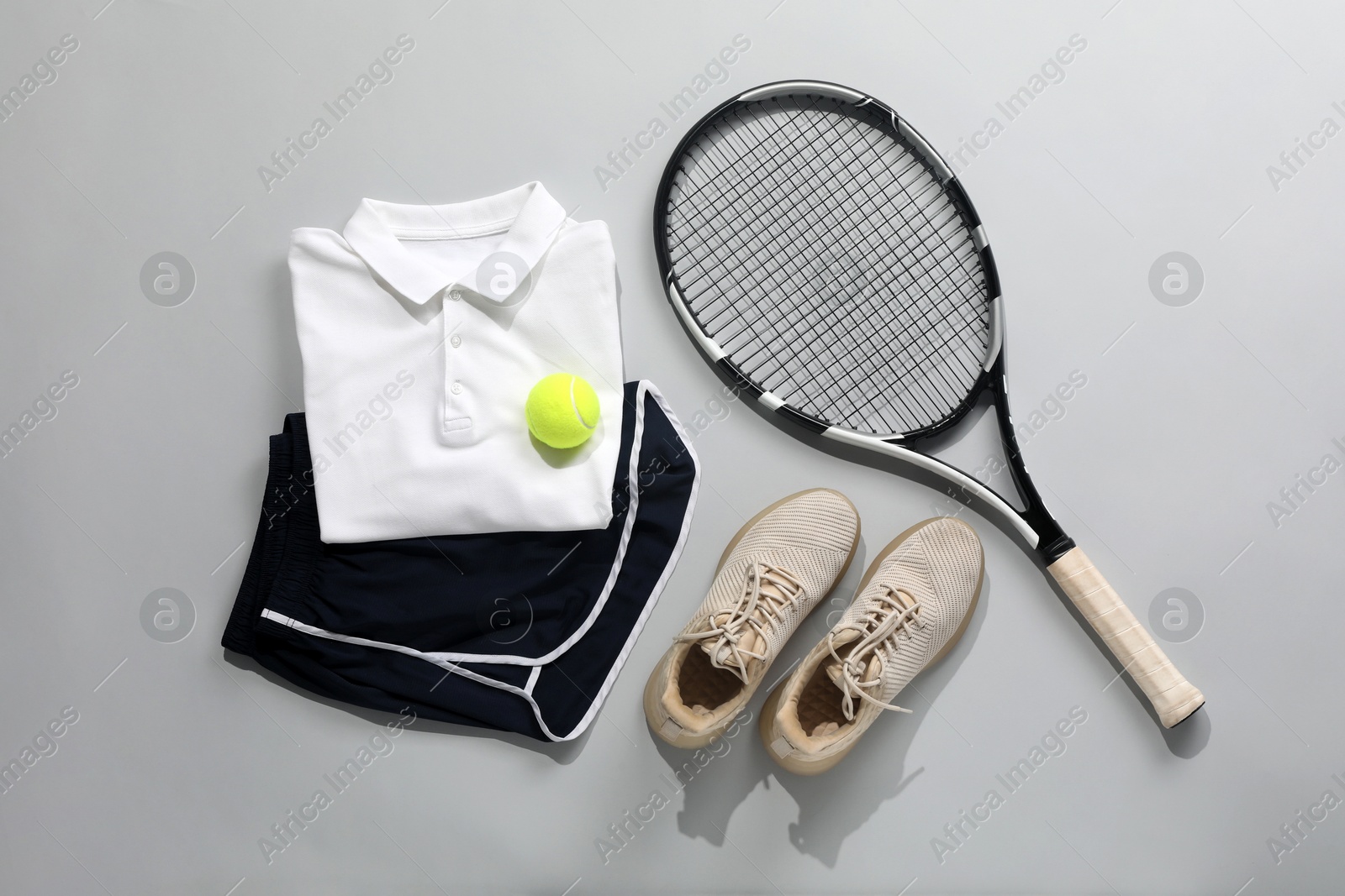 Photo of Tennis racket, ball and sportswear on grey background, flat lay