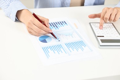 Budget planning. Woman with papers using calculator at white table, closeup