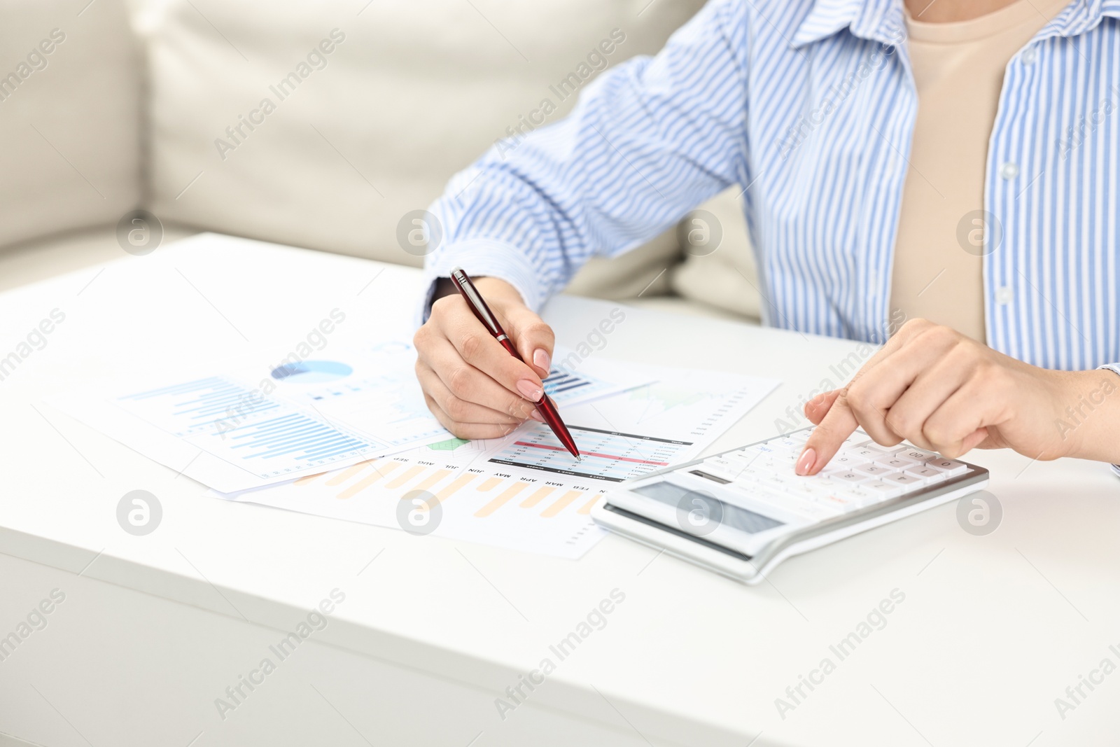 Photo of Budget planning. Woman with papers using calculator at white table, closeup