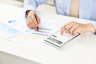 Photo of Budget planning. Woman with papers using calculator at white table, closeup