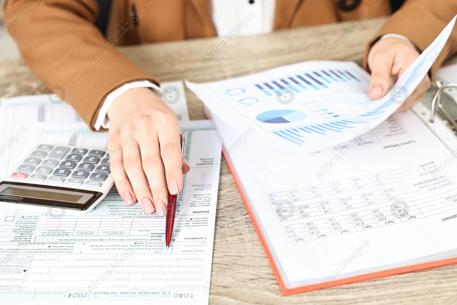 Photo of Budget planning. Woman with papers and calculator at wooden table, closeup