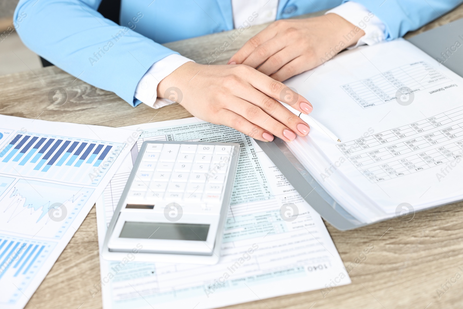 Photo of Budget planning. Woman with papers and calculator at wooden table, closeup