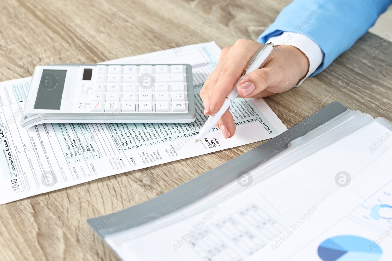 Photo of Budget planning. Woman with papers and calculator at wooden table, closeup