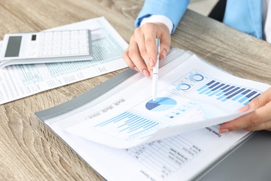 Budget planning. Woman with papers at wooden table, closeup