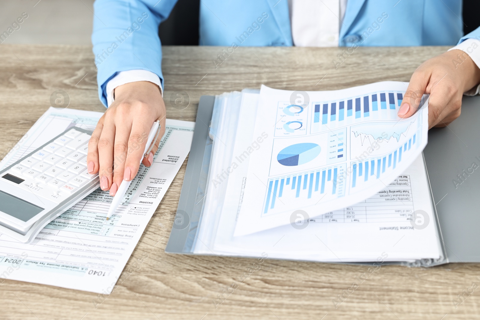 Photo of Budget planning. Woman with papers and calculator at wooden table, closeup