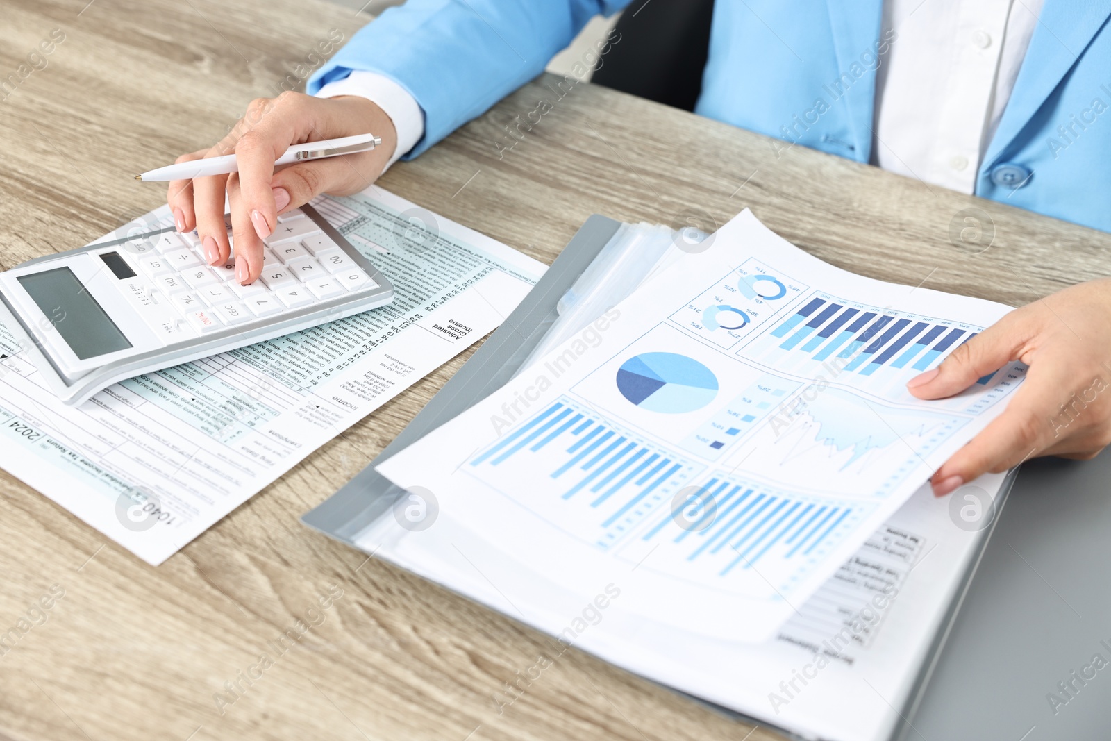 Photo of Budget planning. Woman with papers and calculator at wooden table, closeup