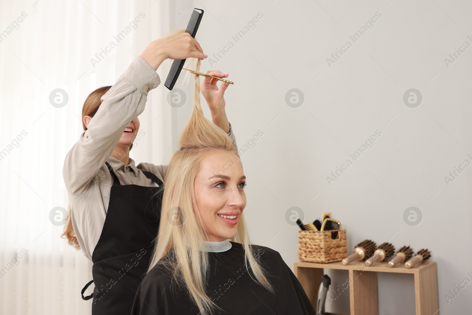 Photo of Hairdresser cutting client's hair with scissors in salon