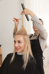 Hairdresser cutting client's hair with scissors in salon