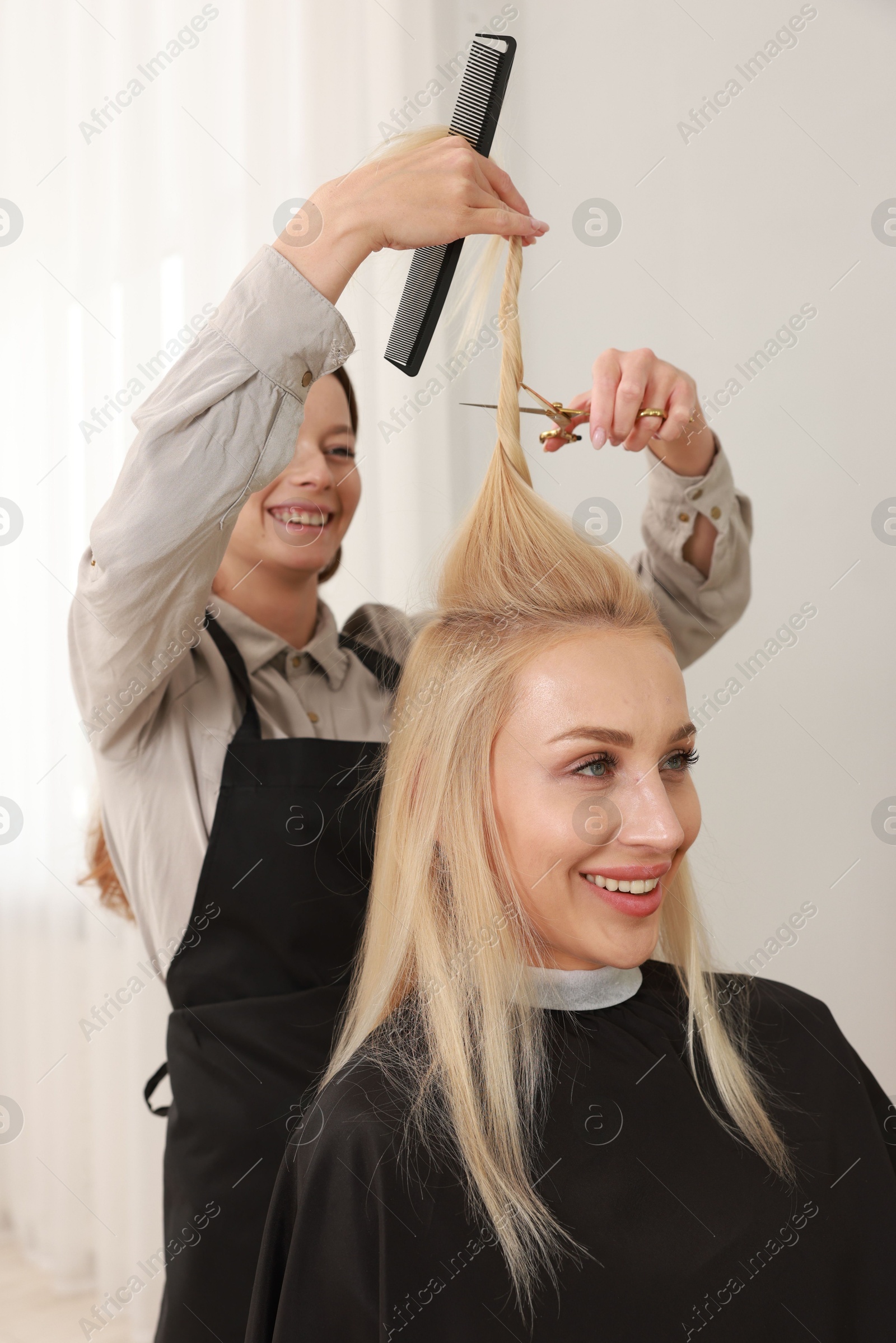 Photo of Hairdresser cutting client's hair with scissors in salon