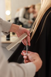 Photo of Hairdresser cutting client's hair with scissors in salon, closeup