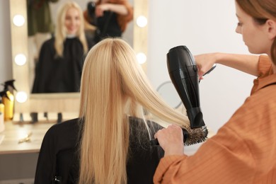 Photo of Hairdresser blow drying client's hair in salon