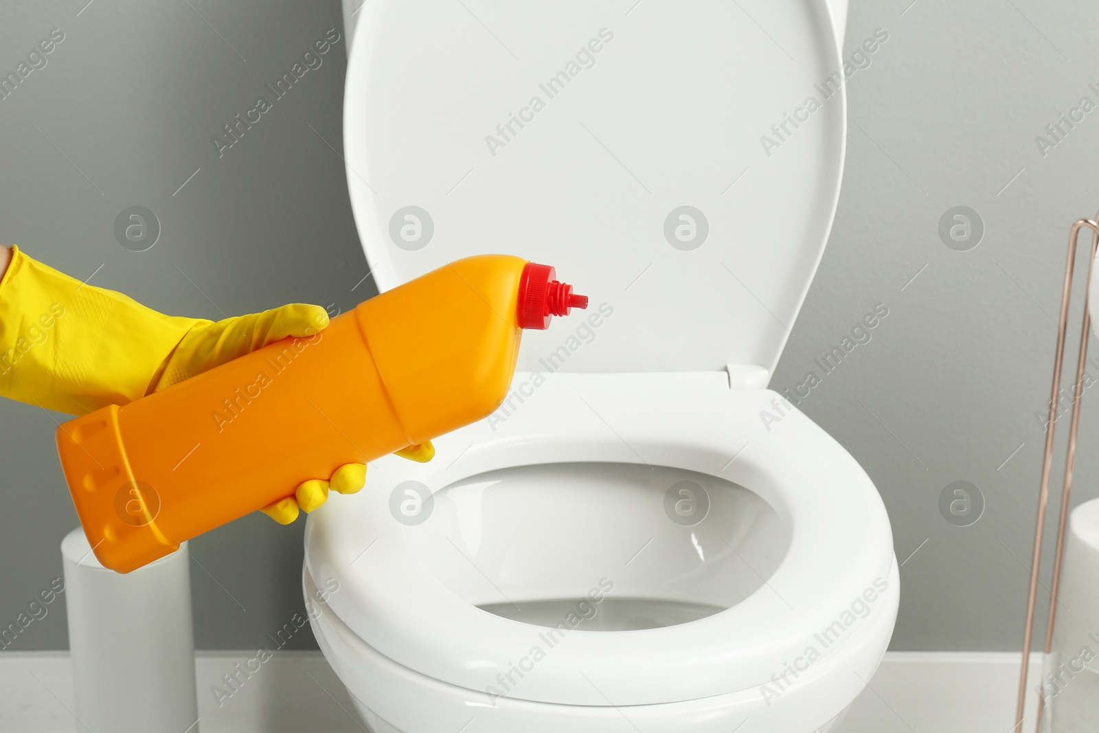 Photo of Woman cleaning toilet with detergent in bathroom, closeup