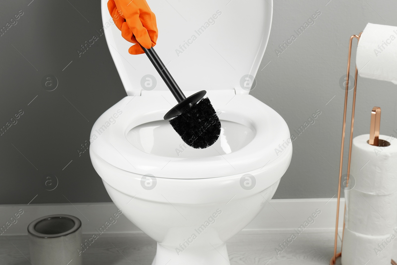 Photo of Woman cleaning toilet with brush in bathroom, closeup