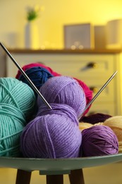 Photo of Colorful yarns and knitting needles on coffee table indoors, closeup