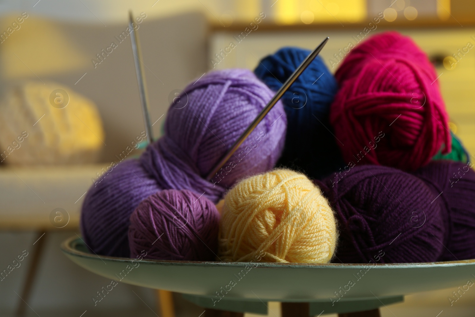 Photo of Colorful yarns and knitting needles on coffee table indoors, closeup