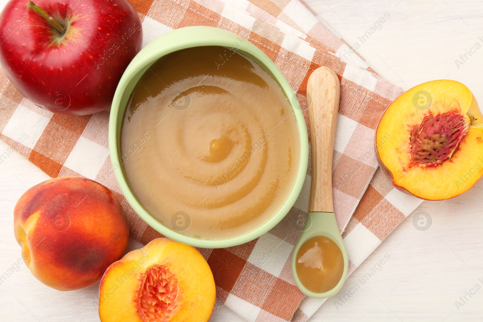 Photo of Delicious baby food in bowl and fresh ingredients on white wooden table, flat lay