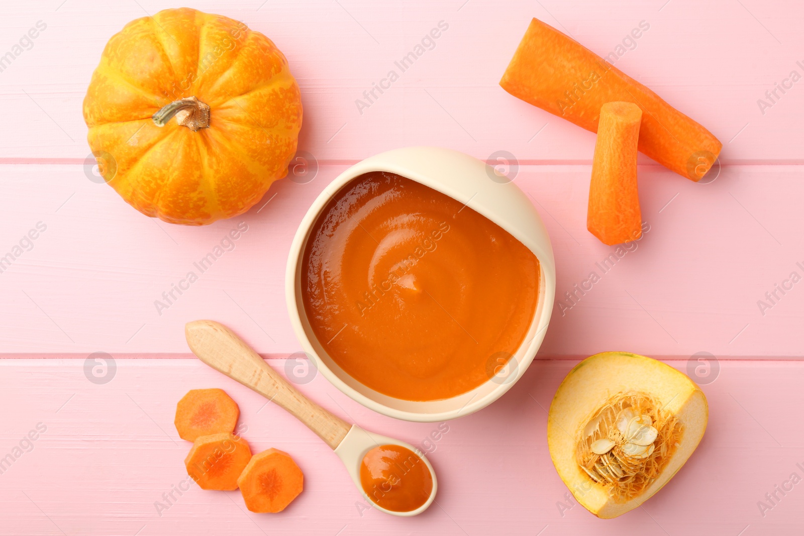 Photo of Delicious baby food in bowl and fresh ingredients on pink wooden table, flat lay