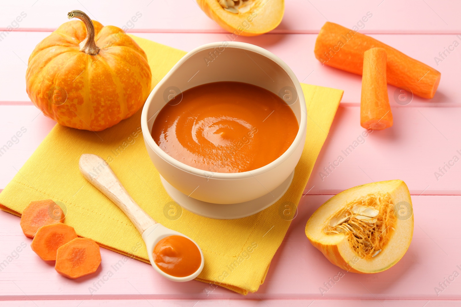 Photo of Delicious baby food in bowl and fresh ingredients on pink wooden table