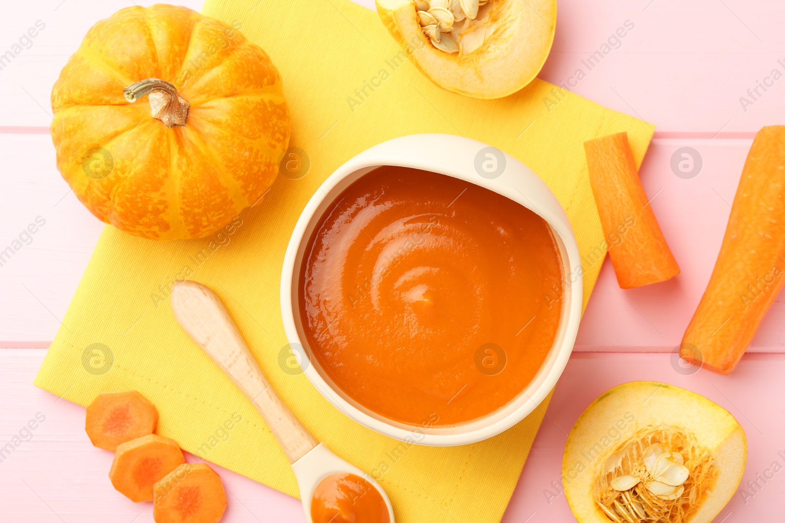 Photo of Delicious baby food in bowl and fresh ingredients on pink wooden table, flat lay