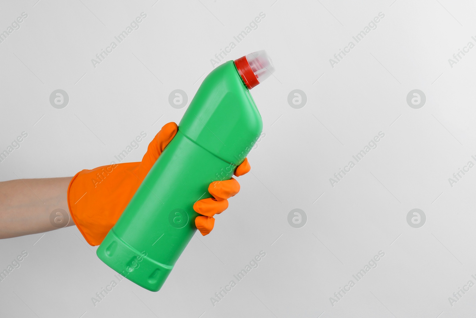 Photo of Woman holding toilet cleaner in bottle on light background, closeup. Space for text