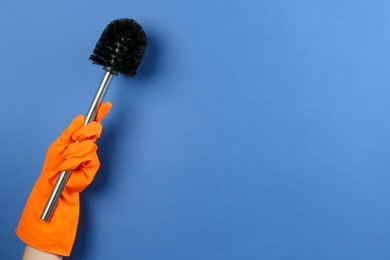 Photo of Woman holding black toilet brush on blue background, closeup. Space for text