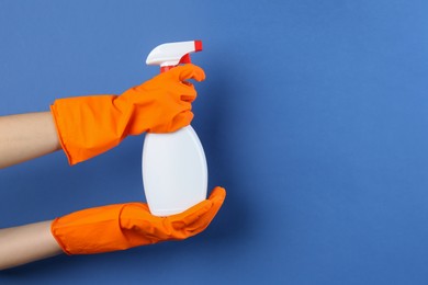 Photo of Woman holding toilet cleaner in spray bottle on blue background, closeup. Space for text