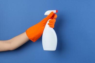 Photo of Woman holding toilet cleaner in spray bottle on blue background, closeup