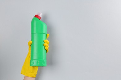 Photo of Woman holding toilet cleaner in bottle on light background, closeup. Space for text